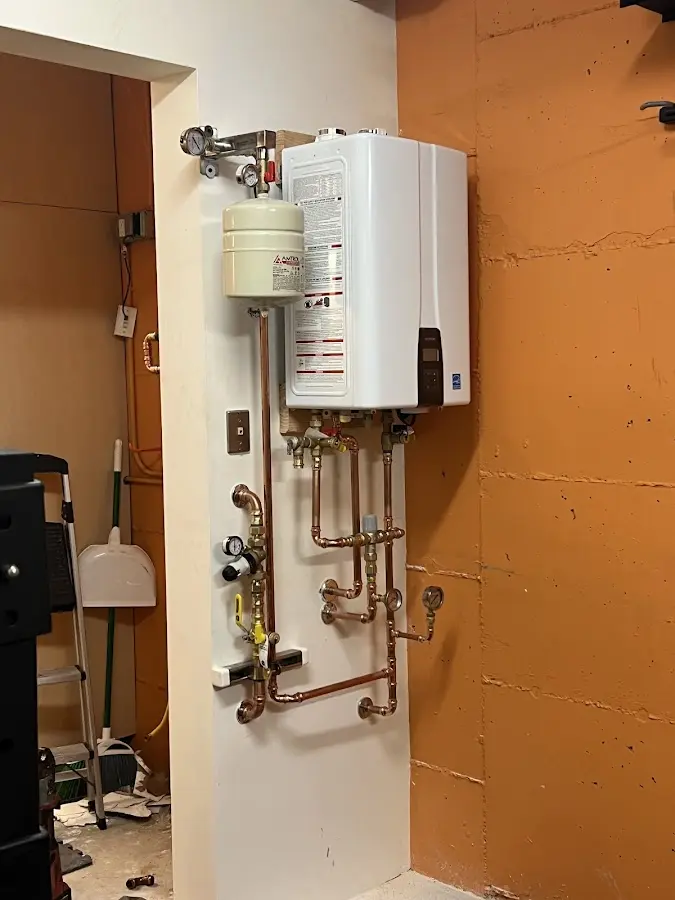Plumbing technician inspecting water heater connections in New Brighton